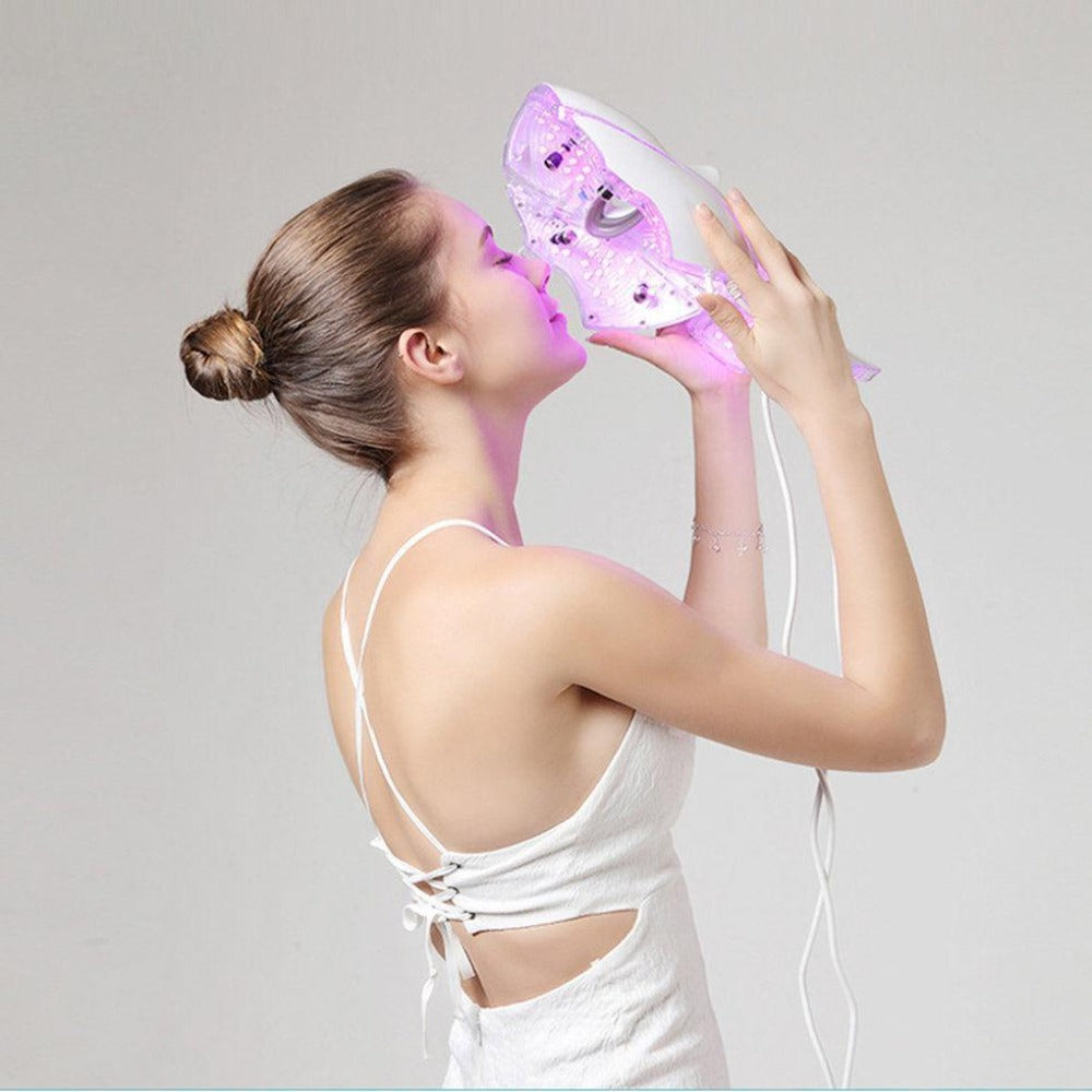 Woman holding a Photon Facial LED Light Therapy Mask in her hand, with seven different color LEDs built-in for treating various skin conditions such as wrinkles, acne, pigmentation, and more. The mask is a breakthrough in skincare and can be easily switched between different colors to target different aspects of the skin.